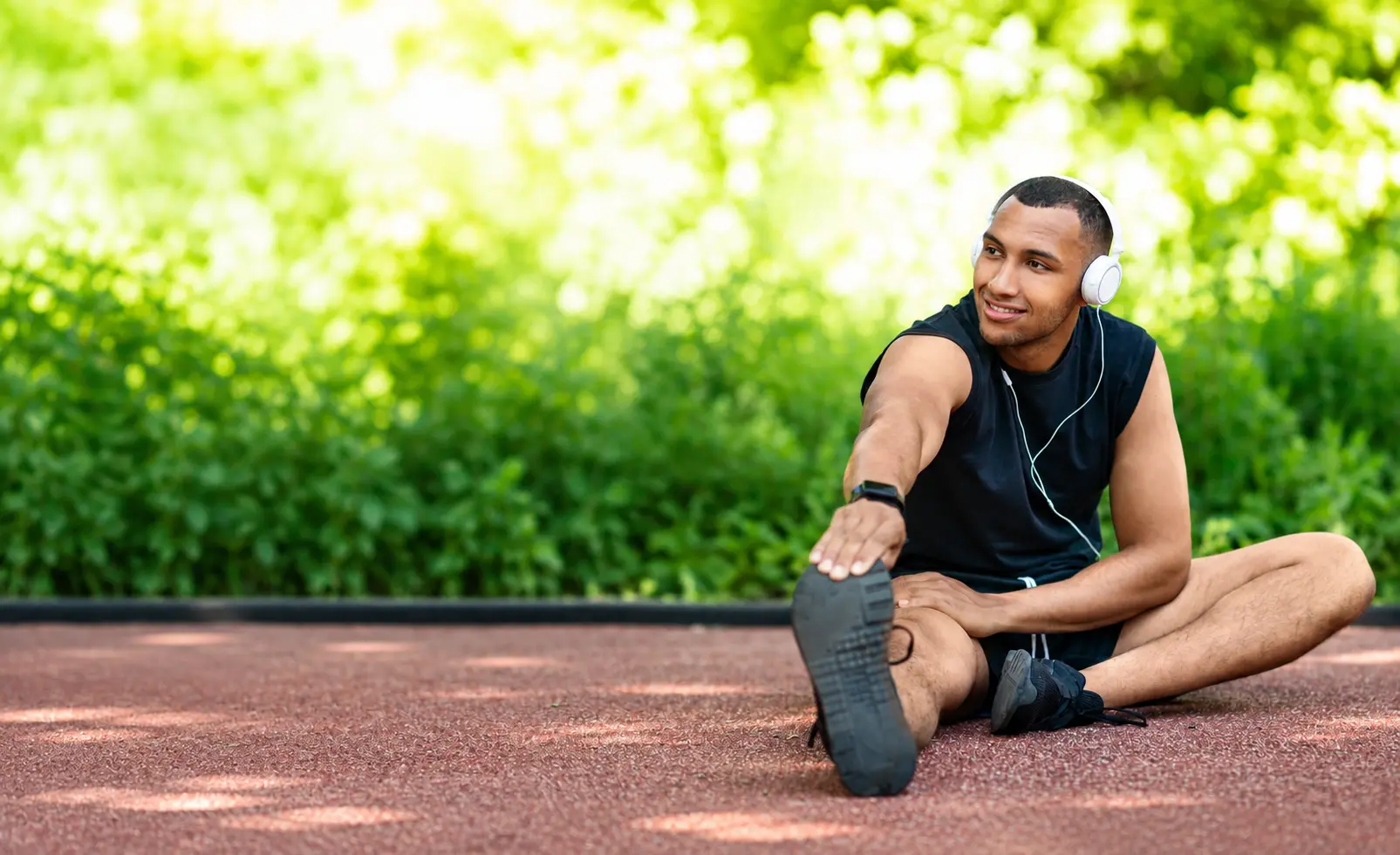 A man wearing headphones stretching outdoors